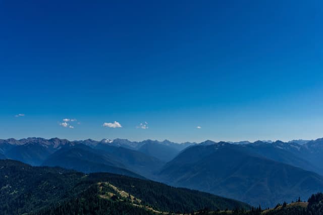 A panoramic view of mountain ranges fading into blue atmospheric perspective under a vivid blue sky