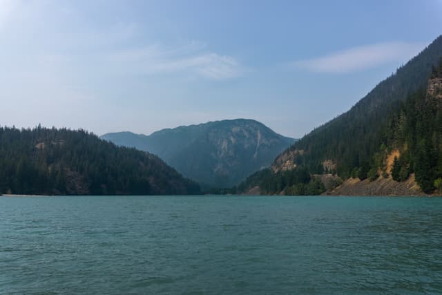 A calm blue lake surrounded by forested hills and mountains