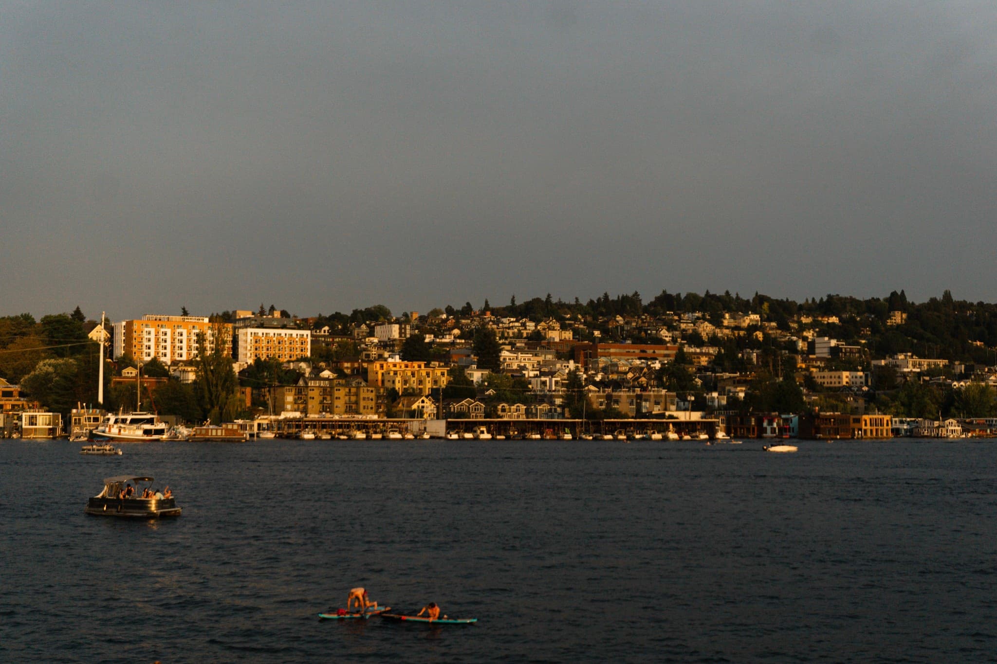 A boat floats on a lake with a residential shoreline and piers under a muted sky, positioned above a section of extreme blur